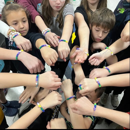 Students showing bracelets they made in class in a circle.